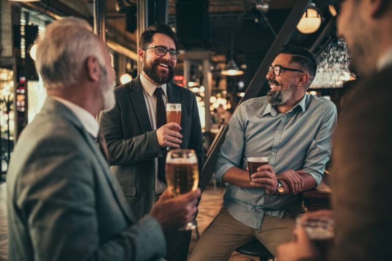 Group of men enjoying drinks and conversation, celebrating a successful week of auto care services.