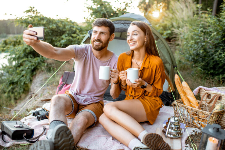 Young couple camping in forest taking selfie, demonstrating connection and finding people.