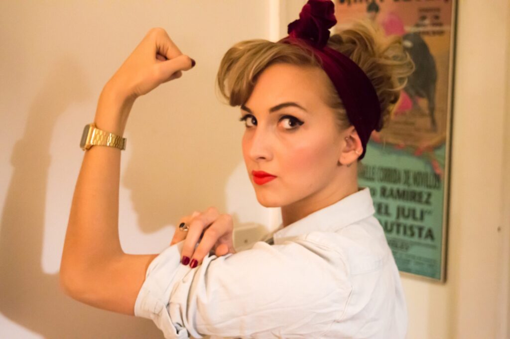 Empowered woman flexing arm, tribute to feminine strength and professional authority in workwear.