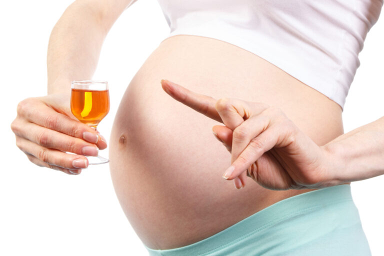 Pregnant woman and glass of wine illustrating health and safety concerns.
