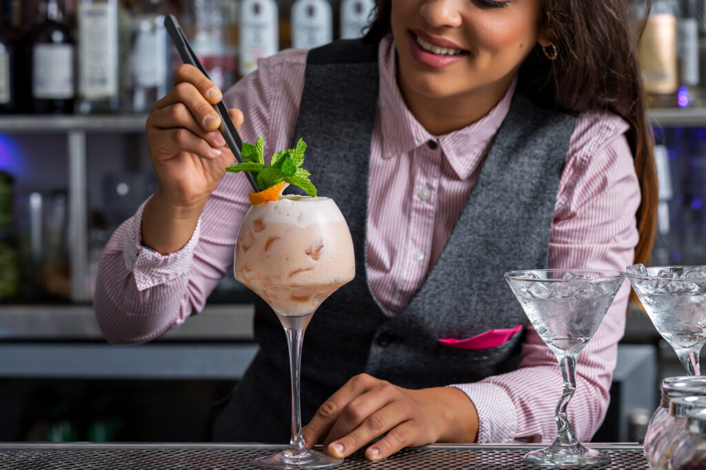 Mixologist decorating cocktail with garnish, illustrating excellence in mixology and beverage blending.