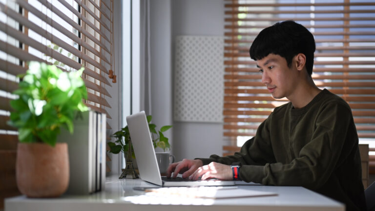 Man researching home maintenance online with laptop, secure home solutions.