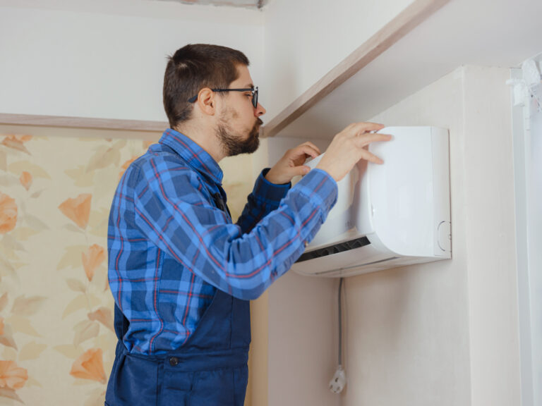 HVAC technician inspecting wall-mounted furnace unit for maintenance and repair.